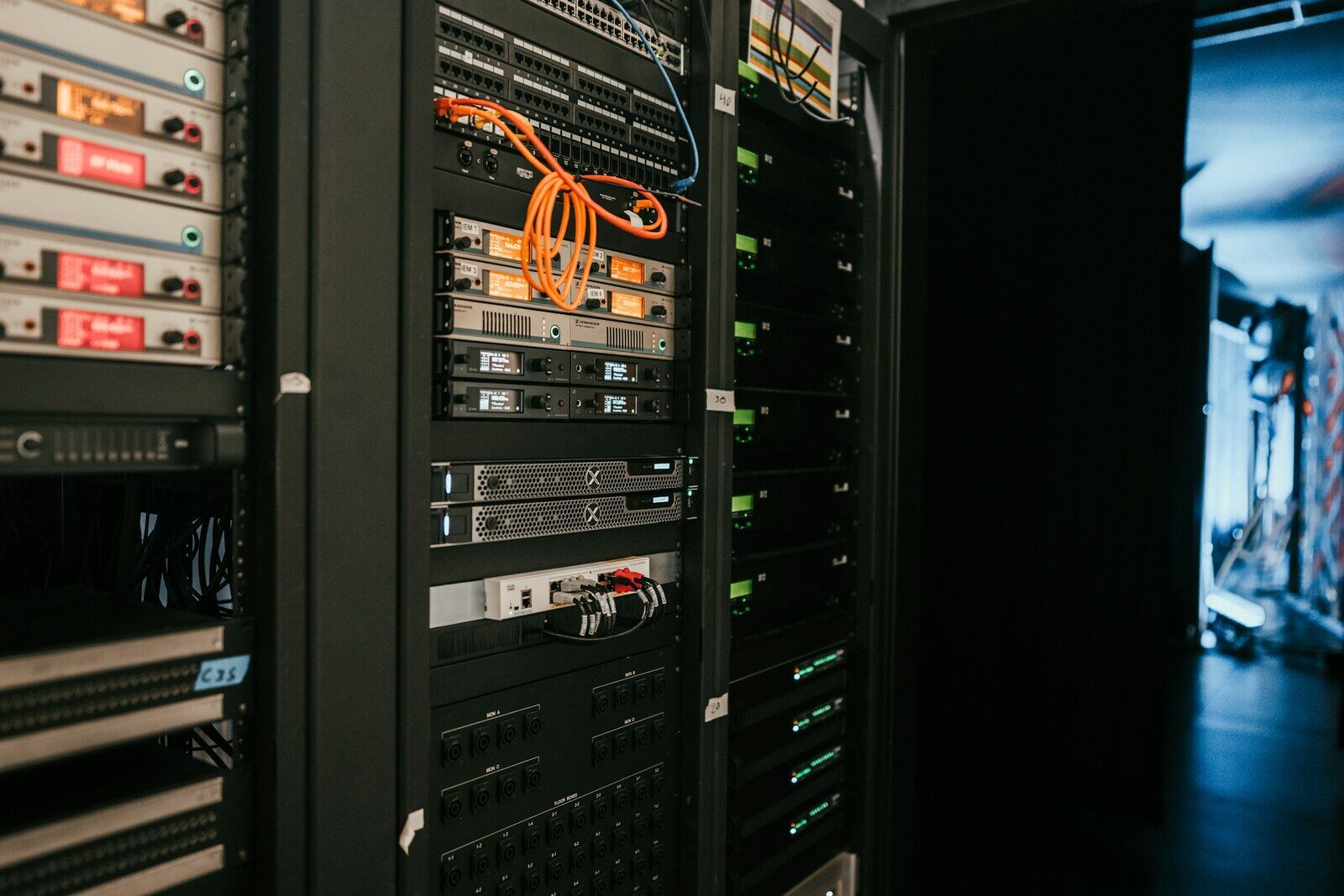 A server rack seen head-on, with tangled cabling and a single orange patch lead.