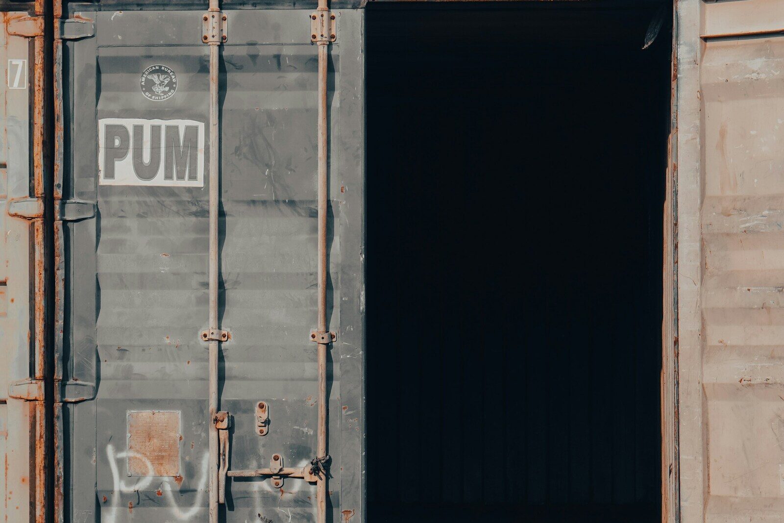 Two doors on one shipping container: one sealed shut, the other standing open on a dark interior.